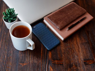 work space of a businessman. view from above . coffee black note and laptop on the desktop with black note. laptop on wooden background