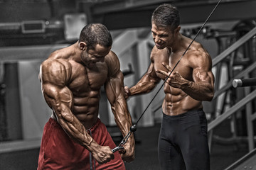Fototapeta na wymiar Bodybuilding Motivation. Two Bodybuilders Train Together at the Gym