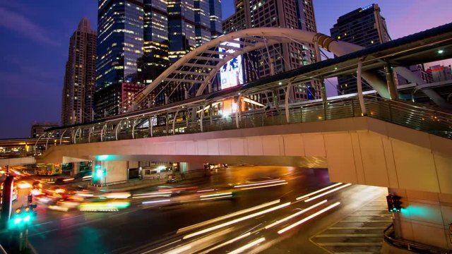 Time-lapse bridge link between BRT and BTS transportation at Chong Nonsi Station in capital city Bangkok, Thailand, dusk to night.