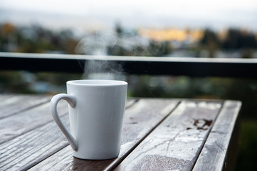 White coffee mug with smoke on the old wooden table with blur background.