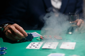 professional poker game. Green poker table with two games. poker player makes a bet by throwing chips on the table