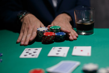 Fototapeta na wymiar professional poker game. Green poker table with two games. poker player makes a bet by throwing chips on the table