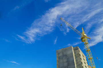 Yellow tower crane. Construction site Unfinished building.