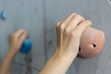 A close up of hands gripping the rock on rock climbing wall © aldarinho