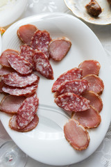 Sliced smoked sausage on a plate. Smoked sausage sliced on a white plate, homemade table.
