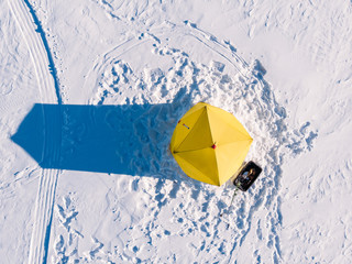 Tent for winter ice fishing, top aerial view, fisherman holding rod in hole lake