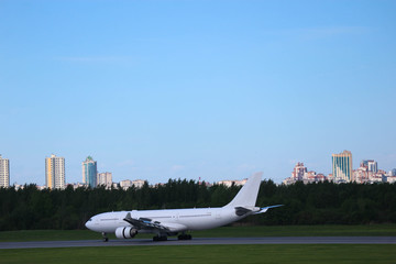widebody white airplane with two engines on the runway after landing in the pulkovo airport, Saint Petersburg, with the silhouette of the city on the background