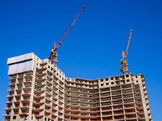 Two cranes on the roof of a house under construction