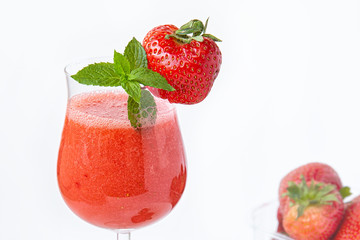 Strawberry smoothie in a glass on a high leg decorated with strawberries and mint on a white background. Strawberry season.Healthy lifestyle.