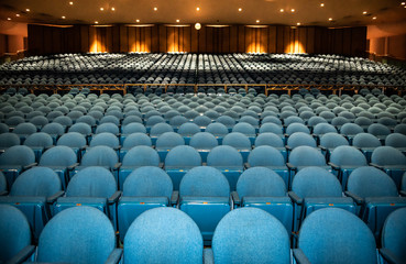 Auditorium with rows of blue seats with railing in back