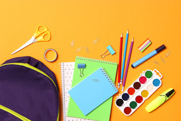 school backpack and school stationery on a colored background top view. Concept back to school.