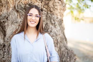 Young woman with glasses smiling in nature