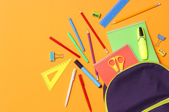 school backpack and school stationery on a colored background top view. Concept back to school.