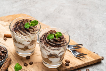 Classic tiramisu dessert in a glass on dark concrete background