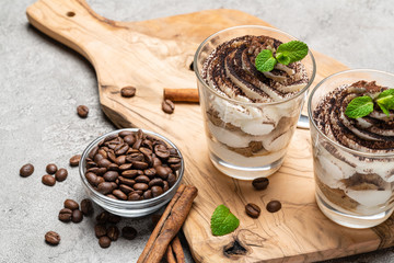Classic tiramisu dessert in a glass on dark concrete background