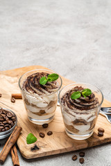 Classic tiramisu dessert in a glass on dark concrete background