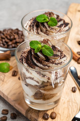 Classic tiramisu dessert in a glass on dark concrete background
