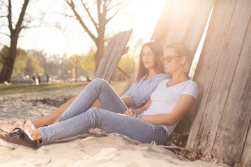 Young beautiful girlfriends relaxing on a sand outdoors