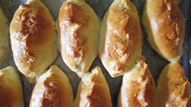 Many traditional delicious baked pasties on tray from oven in bakery. 4K clip with above view