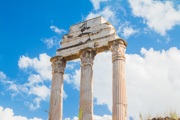 Obraz premium Ruins of Roman empire. Columns of temple of Castor and Pollux on Roman Forum (Forum Romanum), blue sky in background, Rome, Italy
