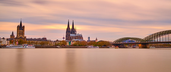 Sonnenuntergang in Köln am Rhein mit Orange Roten Farben am Himmel und Horizont. Blick auf Kölner Dom, Hohenzollernbrücke, Groß St, Martins Kirche und die Kölner Altstadt. Panoarama Hintergrund Poster