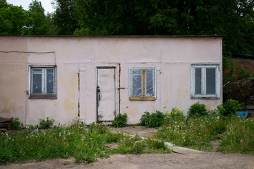 pink barn with plaster on wall stands in the yard. the door is locked. three windows