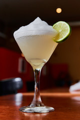Summer fresh salt foam margarita with  lime garnish on bar top in restaurant 