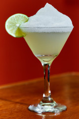 Summer fresh salt foam margarita with  lime garnish on bar top in restaurant 