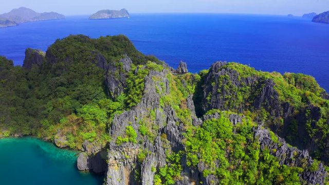 Green trees covered mountains with lagoon on background blue sea in El Nido, Palawan, Philippines. Aerial view 4K