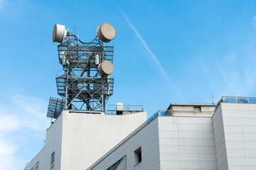 Telecommunication, telephone pole or communication tower with antennas on the top of building outdoor on beautiful blue sky. 4G or 5G telecommunication tower antenna concept.