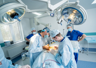 Spinal surgery. Group of surgeons in operating room with surgery equipment. Laminectomy