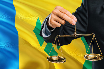 Judge is holding golden scales of justice with Saint Vincent And The Grenadines waving flag...
