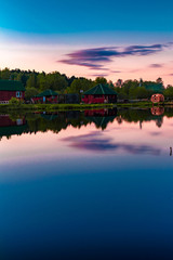 Fototapeta premium Small village red houses reflects in clearly still water at evening