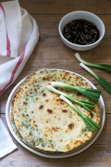 Homemade appetizing scallion pancakes and a bunch of green onions. Rustic style.