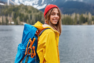 Rear view of happy young European woman enjoys nice serene day, nature landscape scenery, carries...