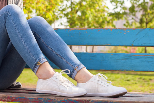 White sneakers on girl legs in blue jeans