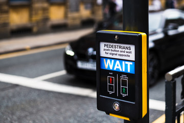 Pedestrian Crossing button in Leeds City Centre that says WAIT for people to cross the road