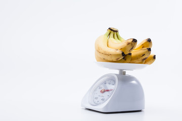 Bunch of bananas on scales isolated on white background