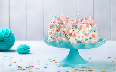 Vanilla buttercream Birthday cake with colorful sprinkles over a neutral background.