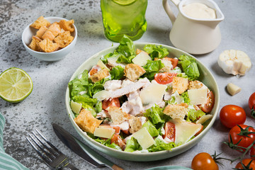 Caesar salad with chicken breast on gray background 