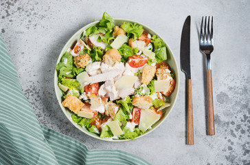 Caesar salad with chicken breast on gray background 