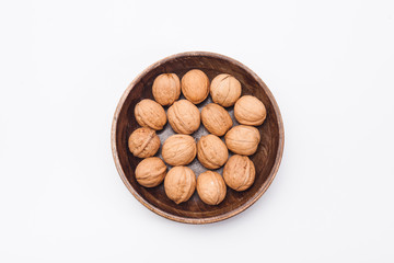 Wooden plate with walnuts isolated on white