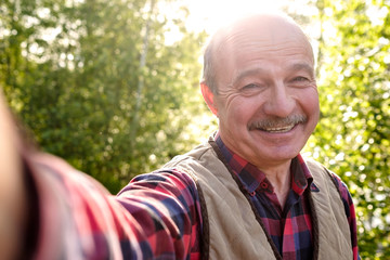 Selfie from handsome senior hispanic man on sunny day. Cheerful senior man making a photo on...