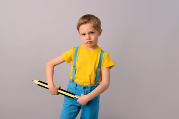 Little boy with a big pencil ready for school and study. Concept of education and learning.