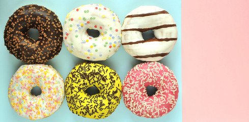 Delicious donuts on light pastel color background.