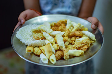 Serving indian fried snacks in plate and holding