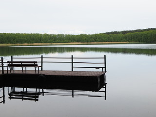 Old wooden pier on the lake with bench