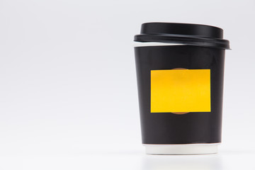 Black plastic paper coffee cup on white take away with yellow post note