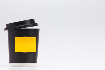 Black plastic paper coffee cup on white take away with yellow post note