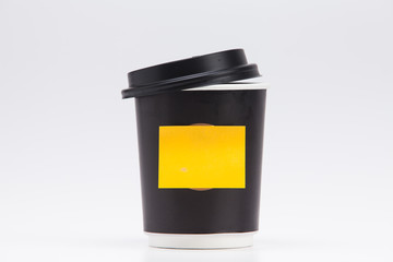 Black plastic paper coffee cup on white take away with yellow post note